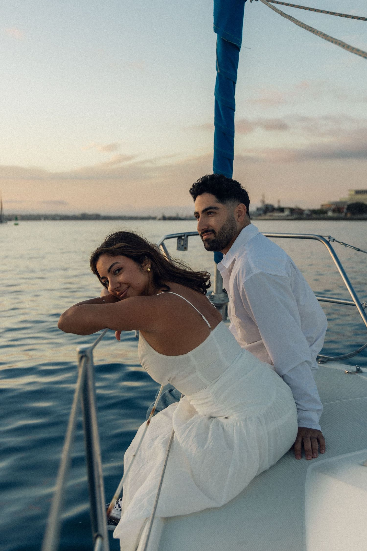 A couple enjoying a romantic sunset moment together on a boat sailing across calm waters near the coastline.