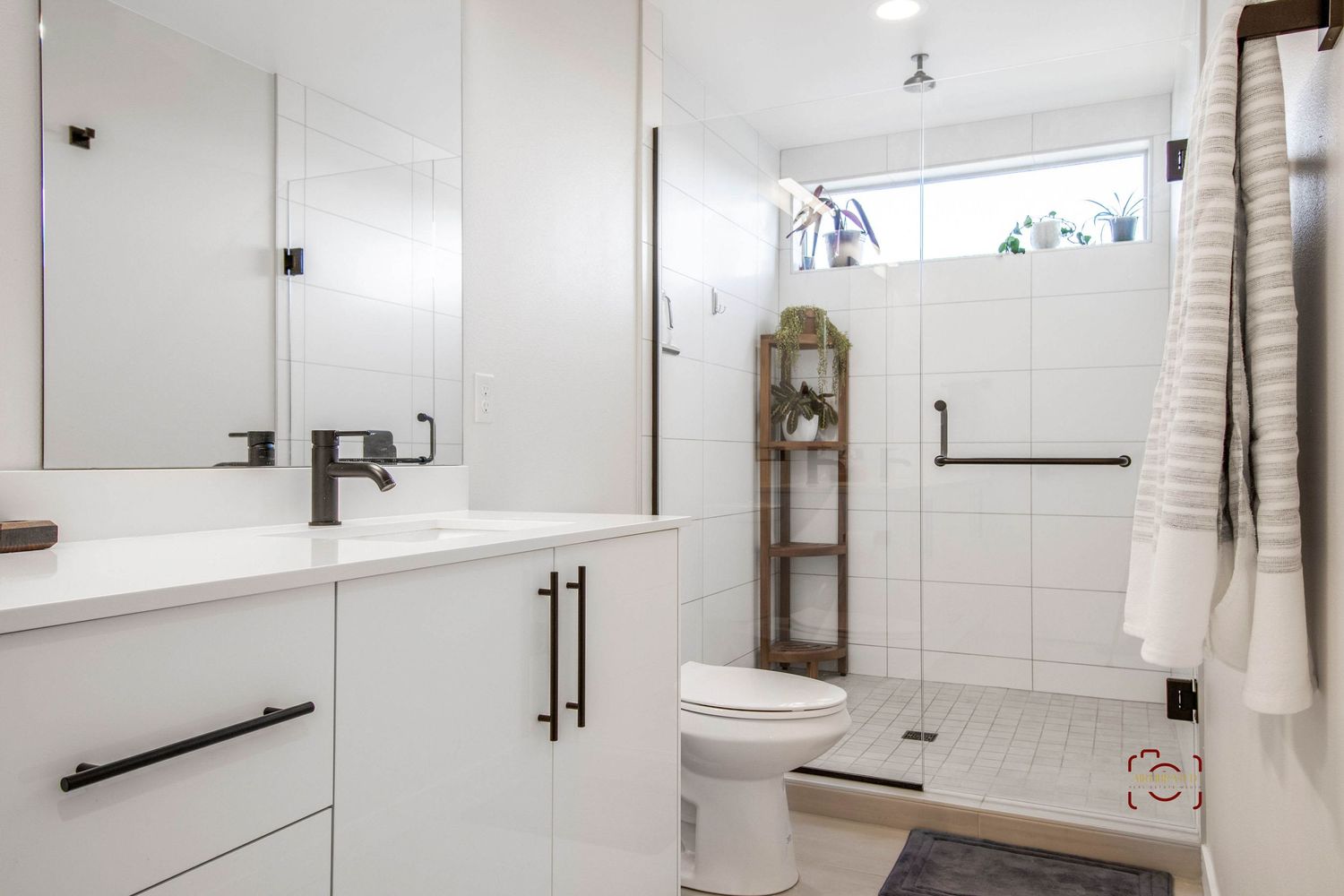 Modern white bathroom interior with floating vanity, matte black hardware, and subway tile shower enclosure.