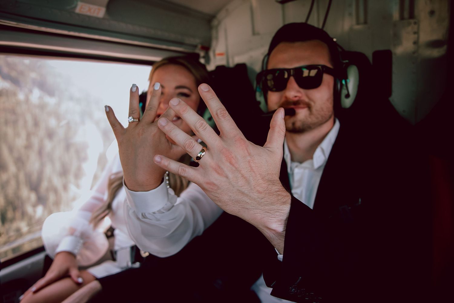 Candid moment showing wedding rings and laughter inside helicopter or small aircraft.