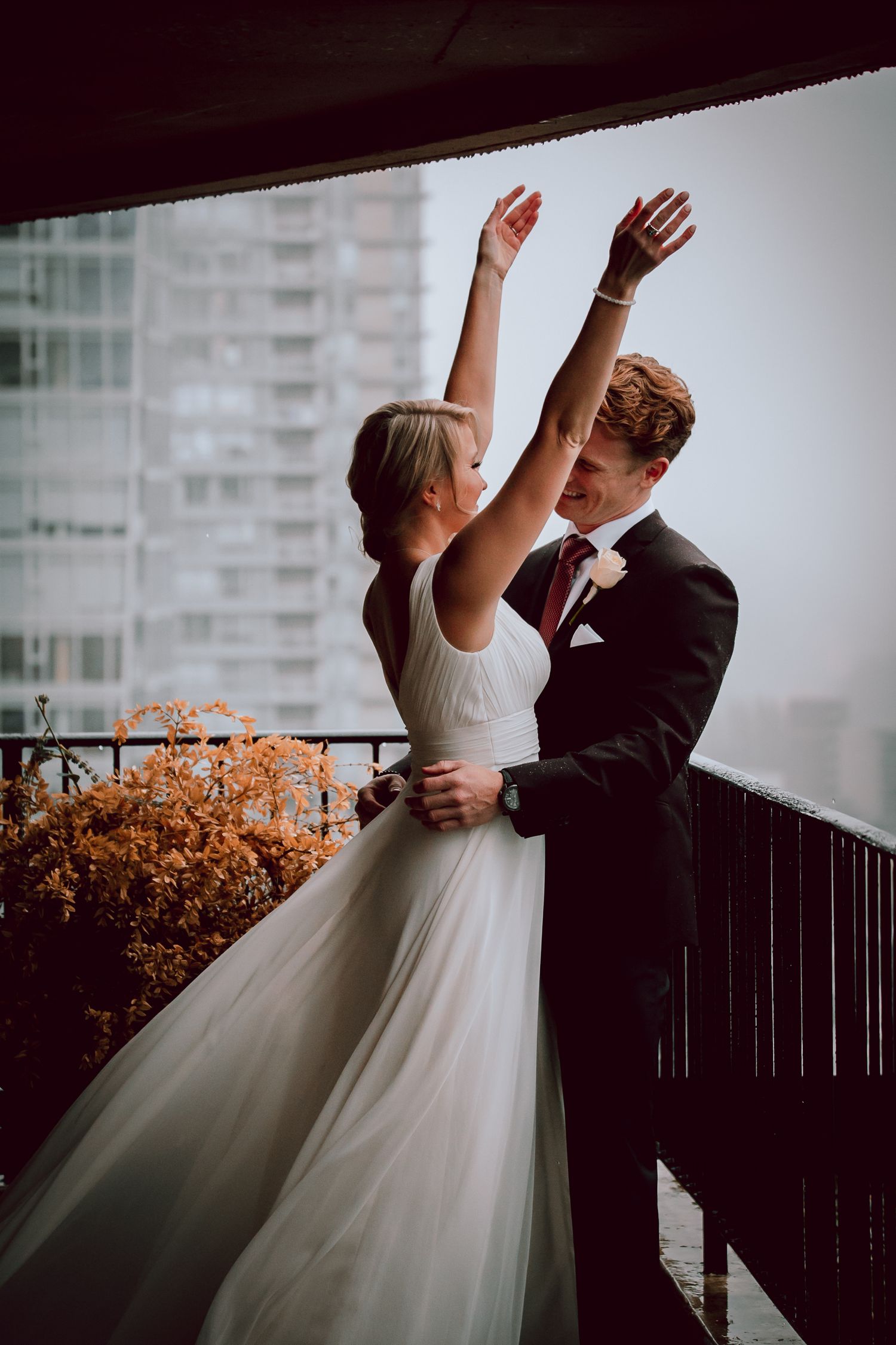 Newlyweds sharing a romantic dance moment on an urban balcony.