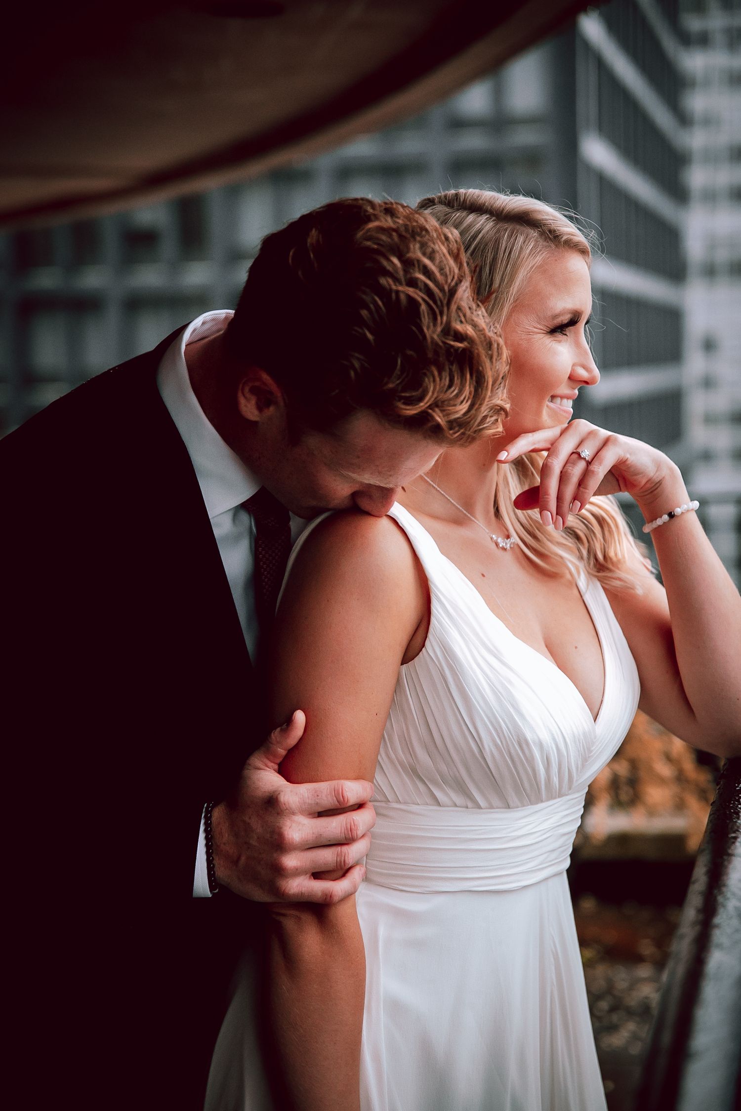 Intimate wedding portrait of couple in formal attire on city balcony.