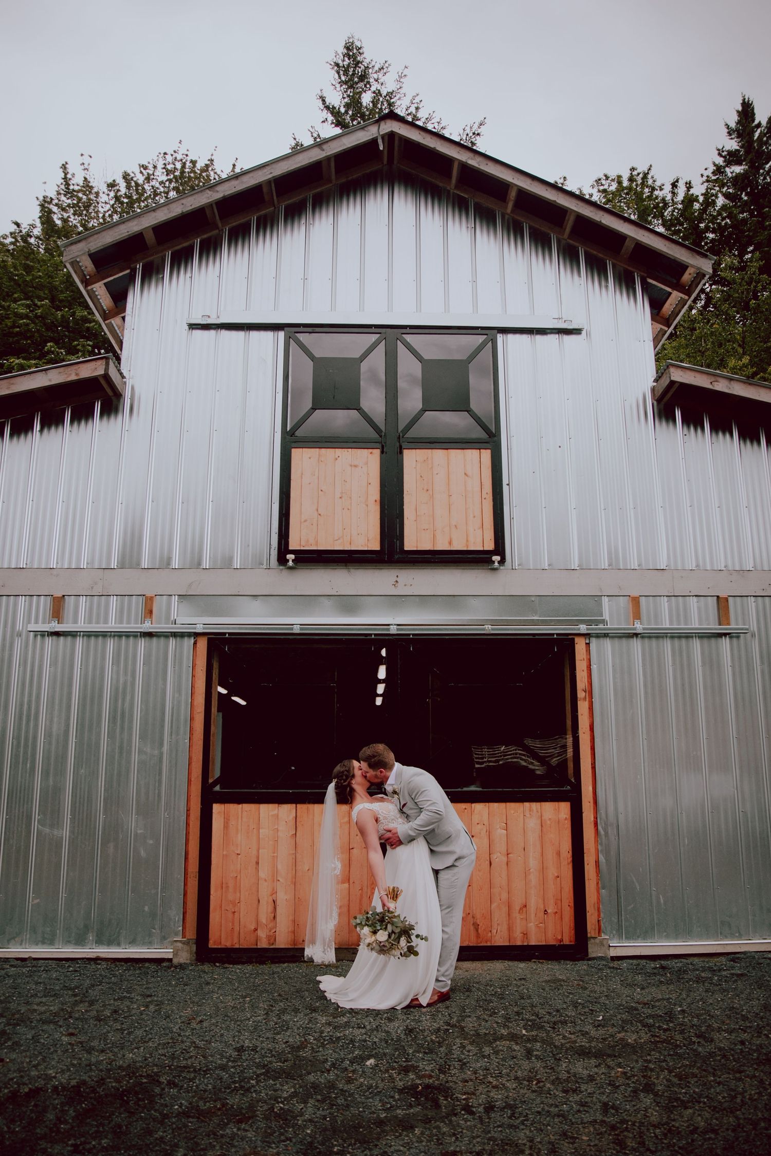 Wedding couple sharing a romantic moment outside a white rustic barn.