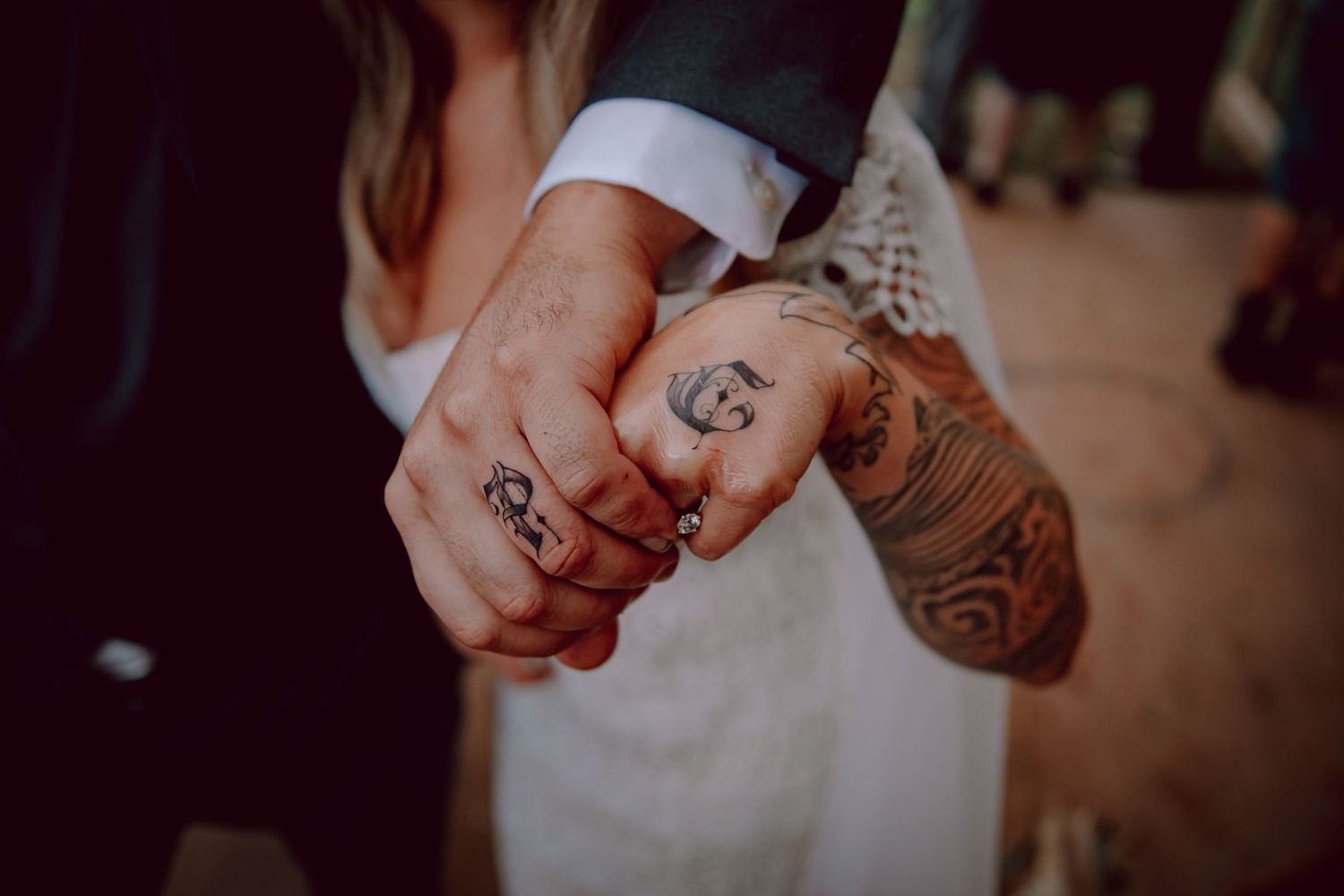 Close up of tattooed hands with wedding rings being held together.