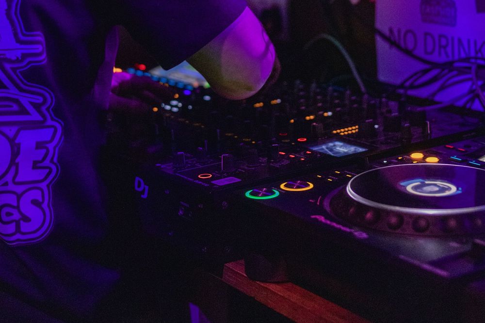 DJ equipment and turntables illuminated by vibrant purple lighting at a nightclub performance setup.