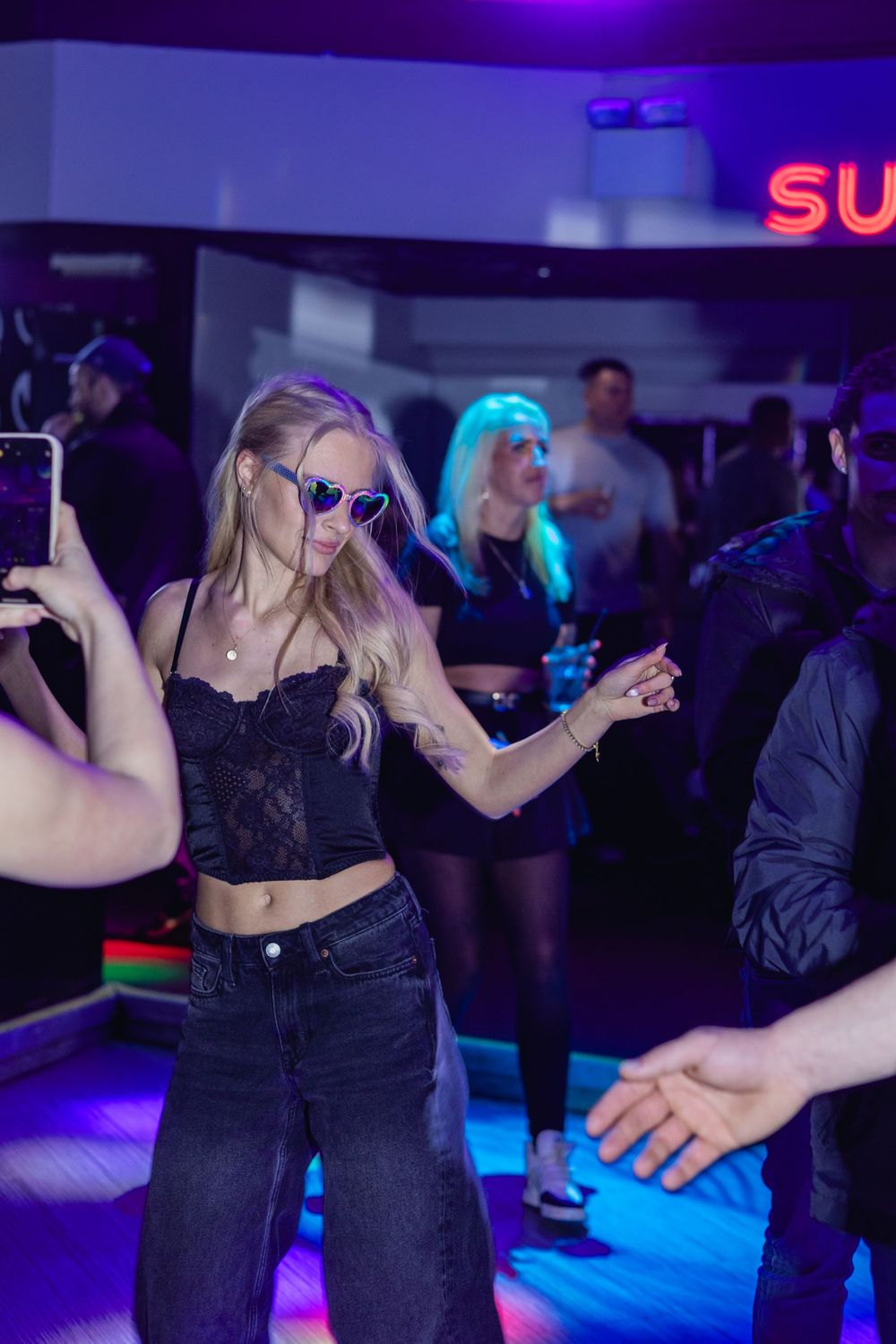 People dancing together at a nightclub with purple and blue lighting effects.