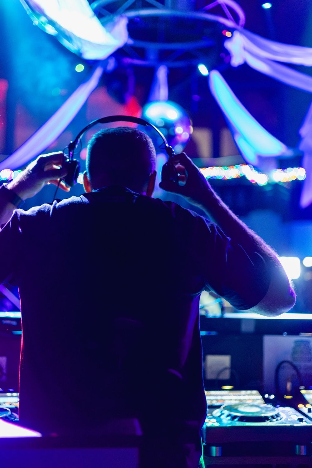DJ booth silhouetted against vibrant blue stage lighting at a nightclub event.