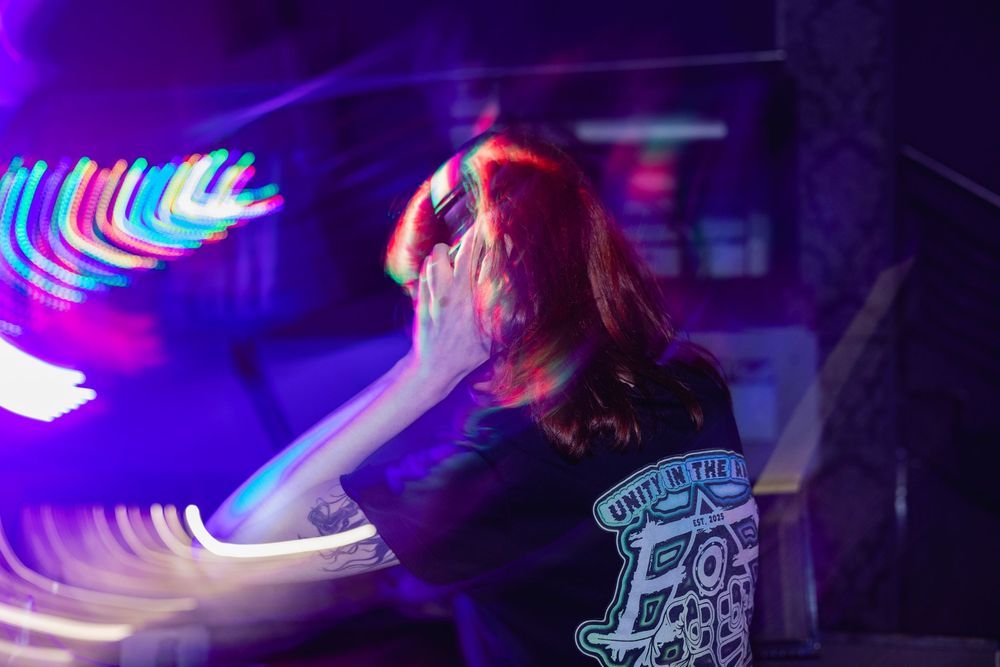 DJ performs at nightclub with vibrant purple and blue lighting creating an energetic atmosphere.