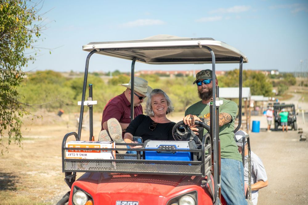 People riding in a golf cart at an outdoor sporting facility.