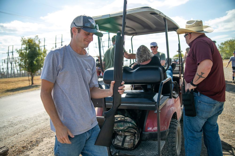 Group gathered around a golf cart at an outdoor sporting event.