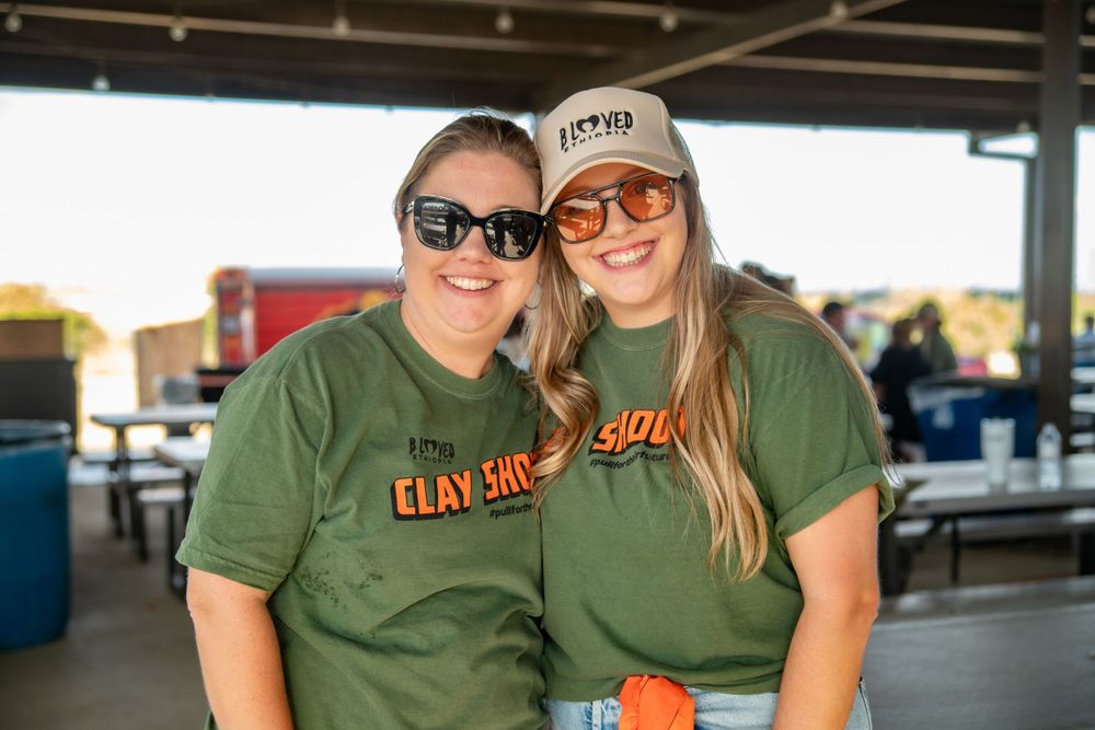 Two people in matching green t-shirts smile at an outdoor event.