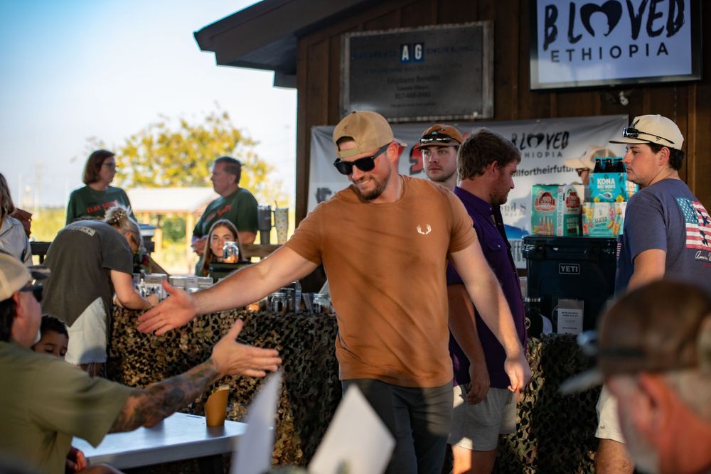 People interacting at an outdoor social gathering with tents and vendors.