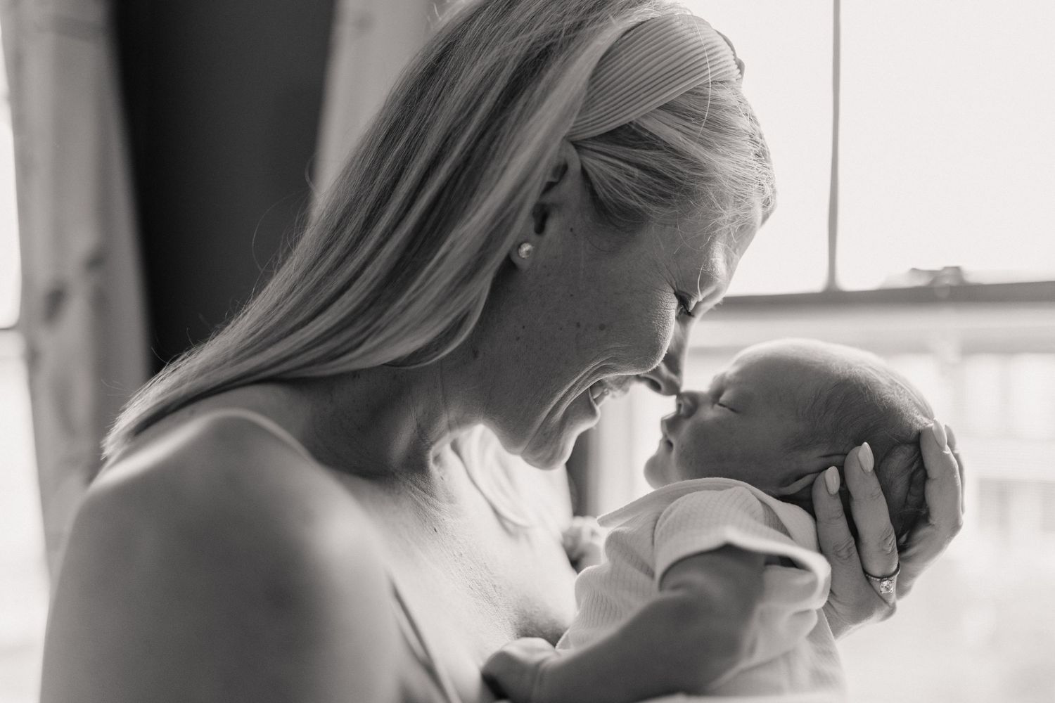 Intimate black and white side profile with soft lighting and window shadows.