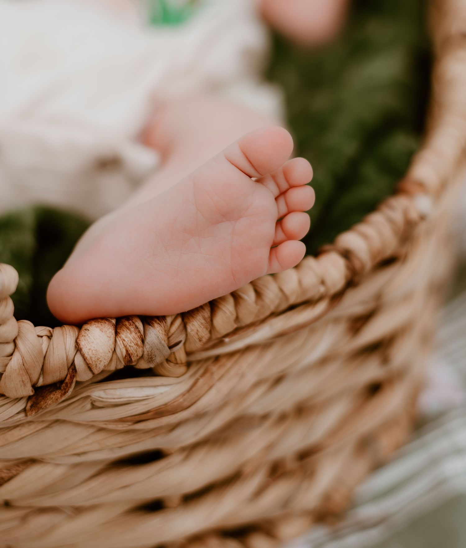Tiny newborn baby feet nestled in soft beige blanket folds creating a serene and peaceful scene.