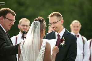 Outdoor wedding ceremony with officiant and couple exchanging vows.