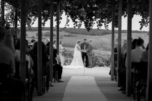 Black and white shot of wedding ceremony in covered outdoor venue with scenic backdrop.