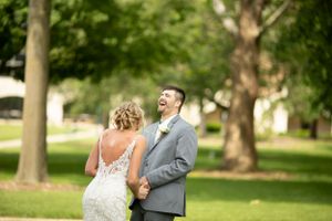 Candid moment between couple laughing together in a park setting during wedding portraits.