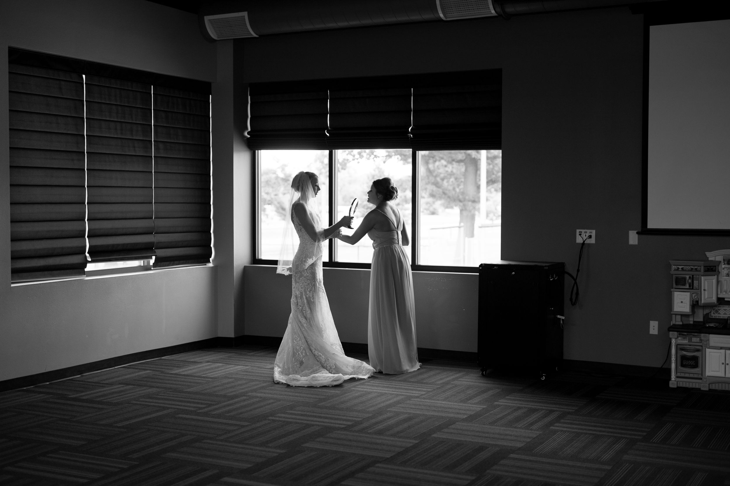 Silhouetted wedding preparations by window in black and white photography.