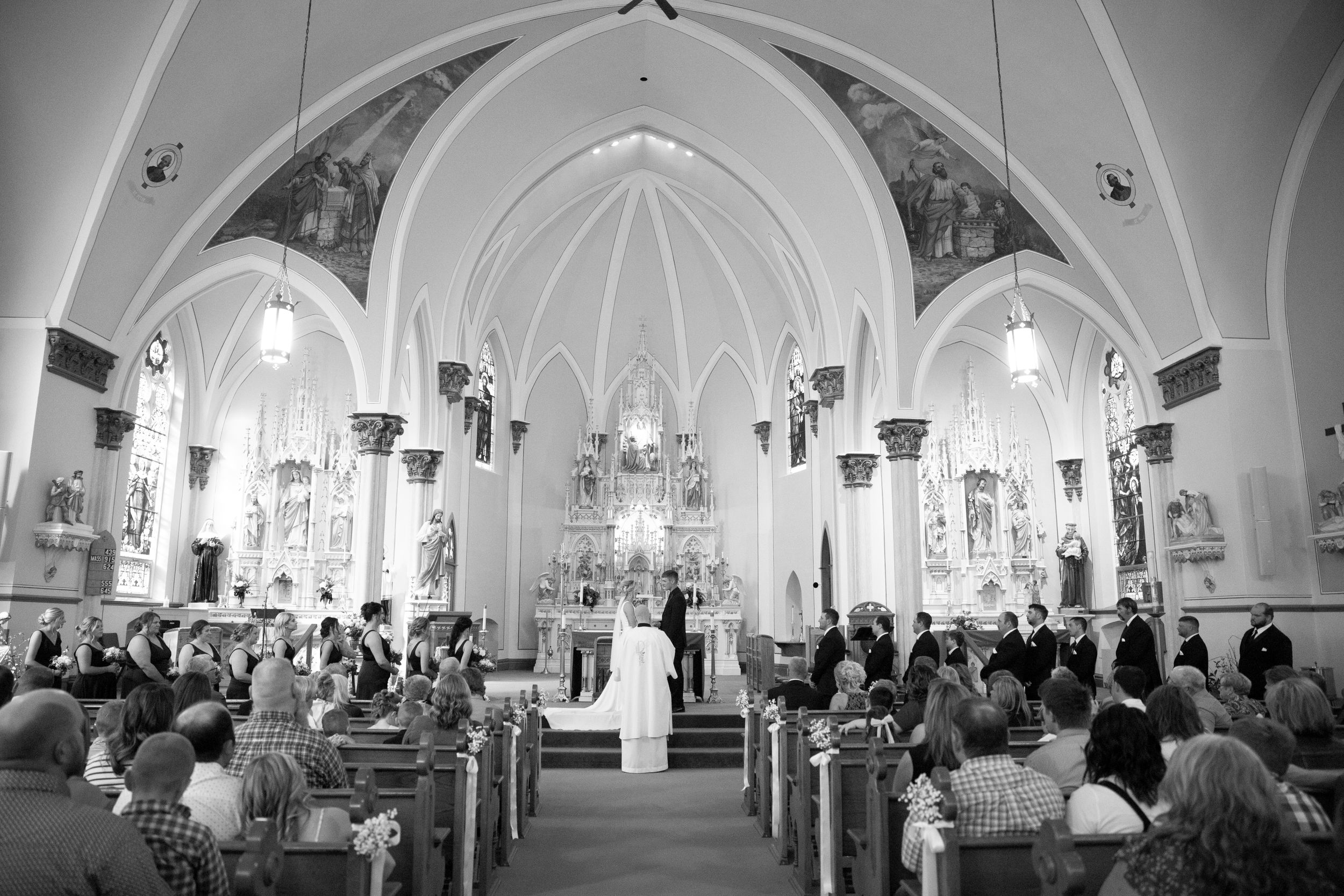 Black and white photograph of a traditional church wedding ceremony with vaulted Gothic architecture.