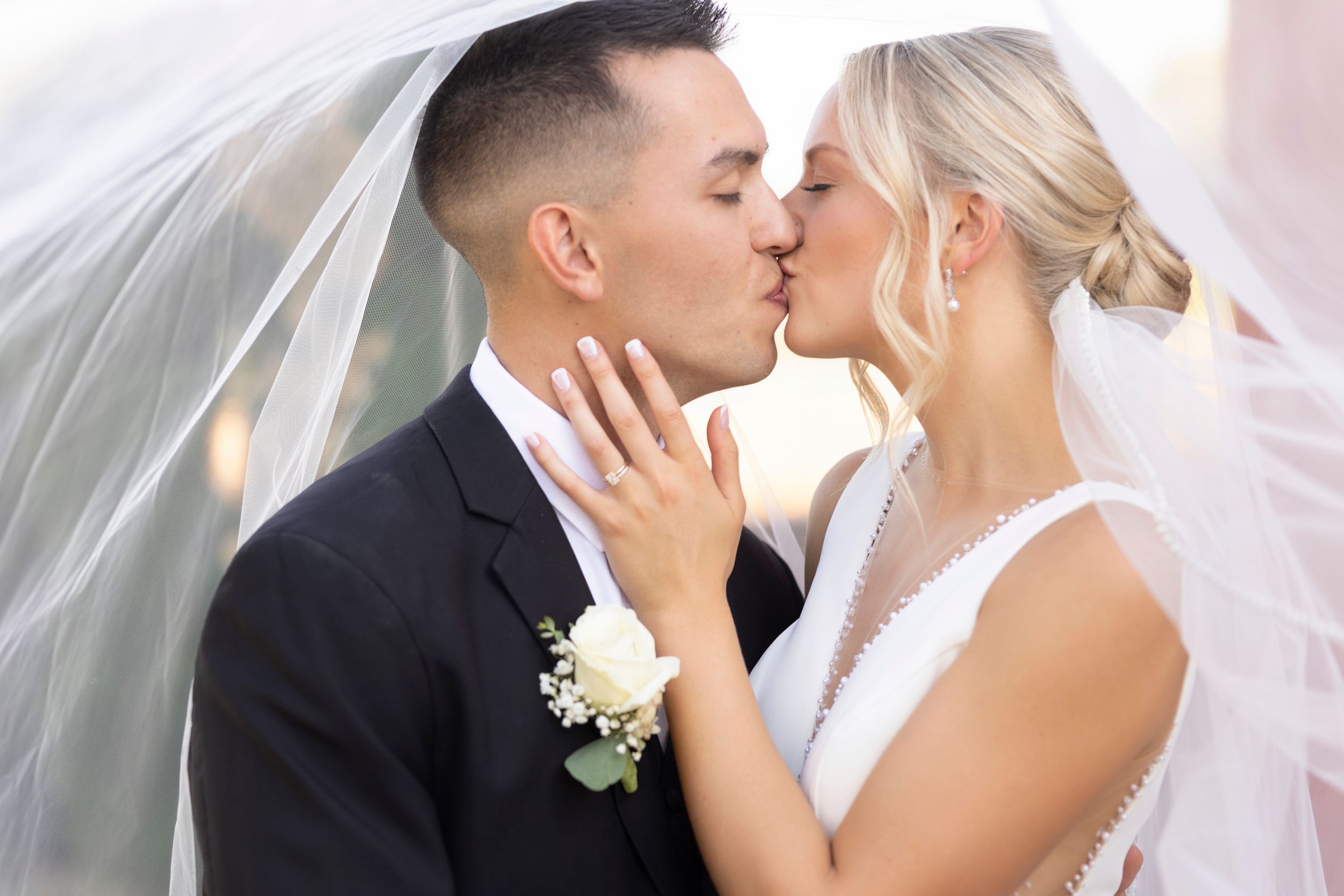 A romantic wedding kiss captured under a flowing white veil.