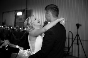 Black and white reception photo of couple's first dance under string lights.