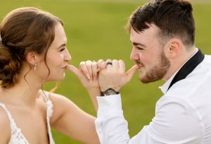 A candid moment of playfulness between newlyweds in white attire.