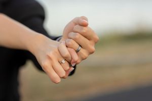 Close-up of hands holding together showing wedding rings.