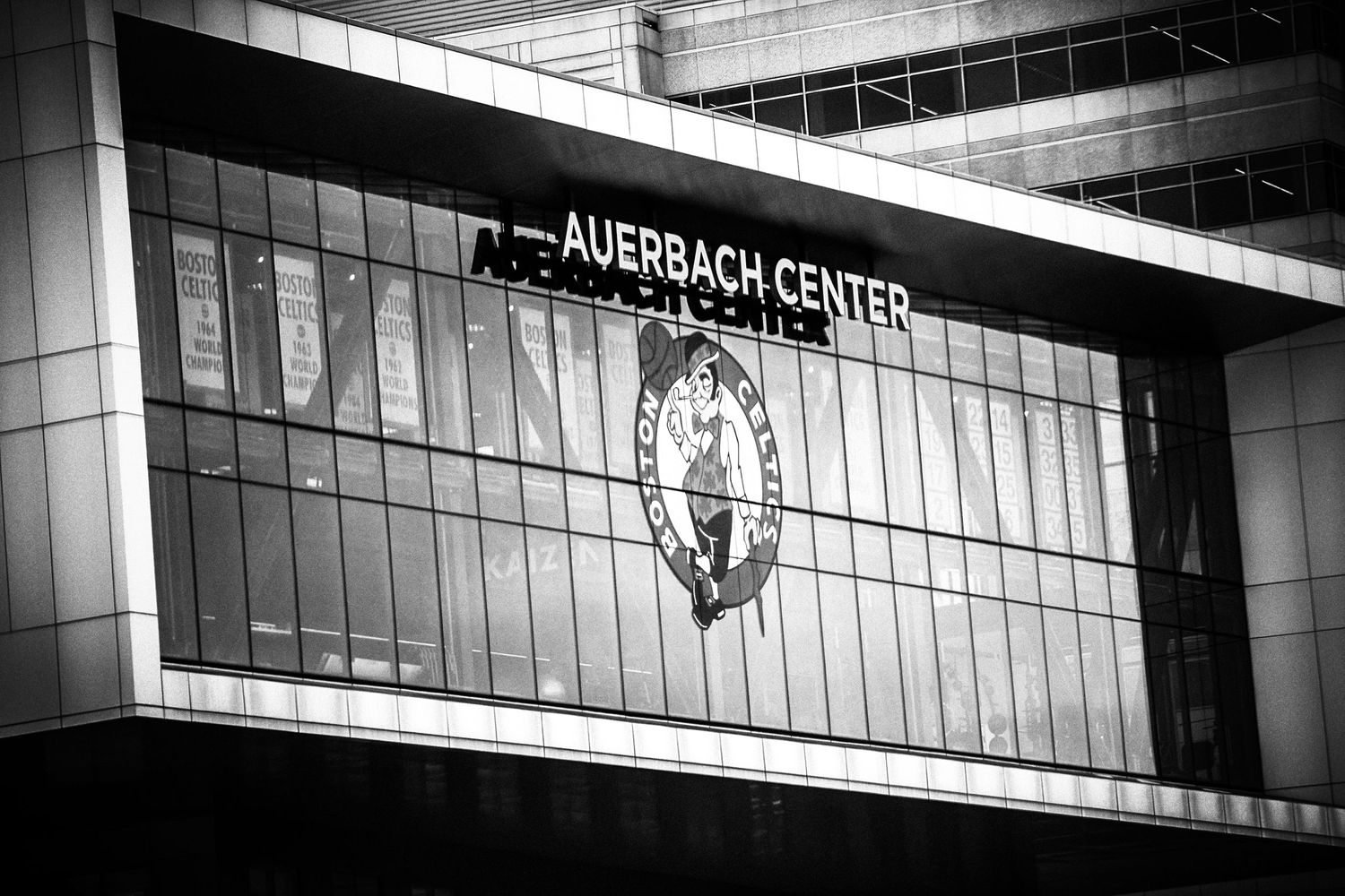 Black and white architectural photo of the Auerbach Center with Boston Celtics logo displayed on modern glass facade.