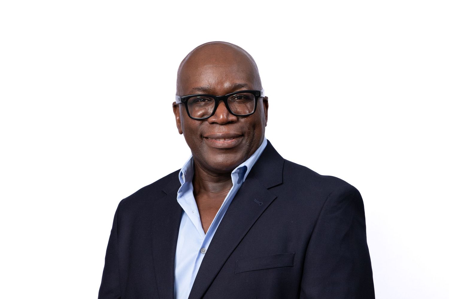 Professional headshot of person wearing glasses and dark blazer against white background.