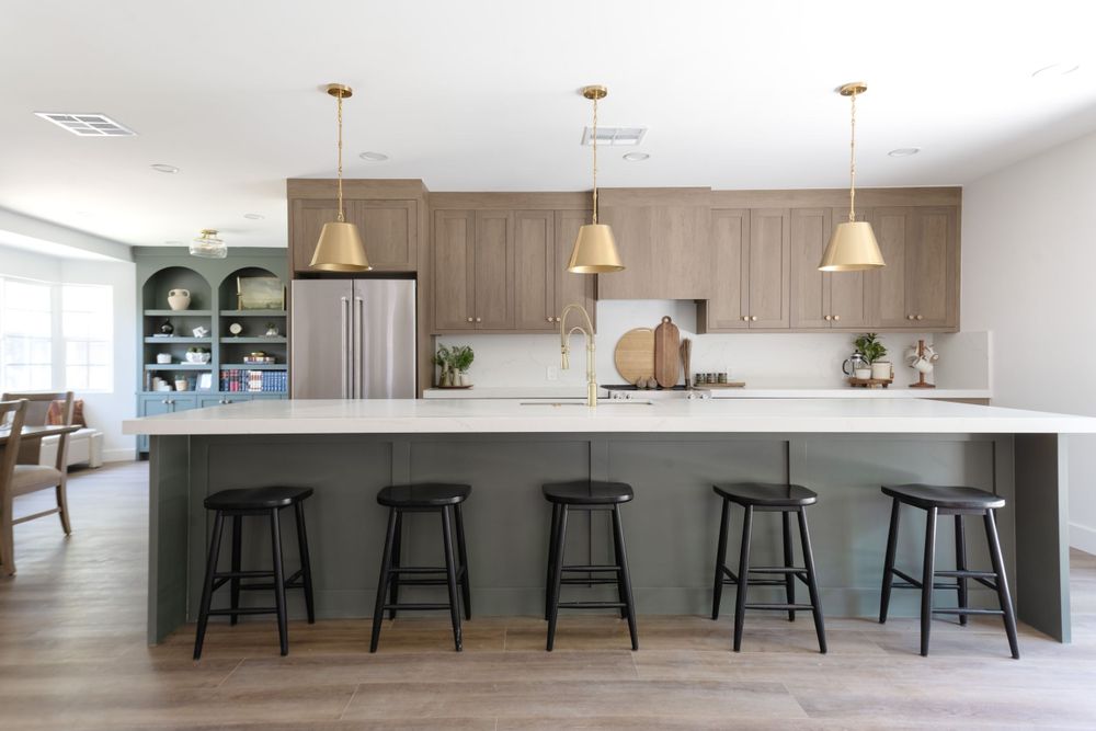 Modern kitchen with wood cabinets, black bar stools, and pendant lighting over a large white island. MLS Photographer, Phoenix Arizona