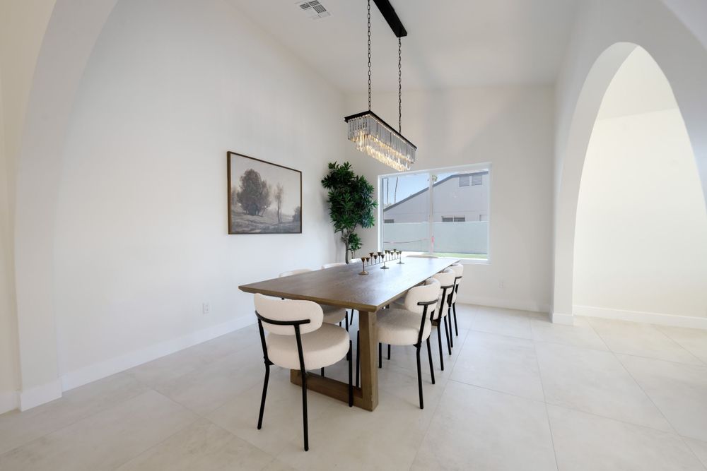 Minimalist dining room with wooden table, black chairs, and modern chandelier under vaulted ceiling. MLS Photographer, Phoenix Arizona