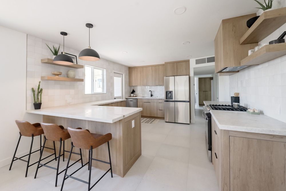 Open concept kitchen with light wood cabinetry, white countertops, and brown leather bar stools. MLS Photographer, Phoenix Arizona