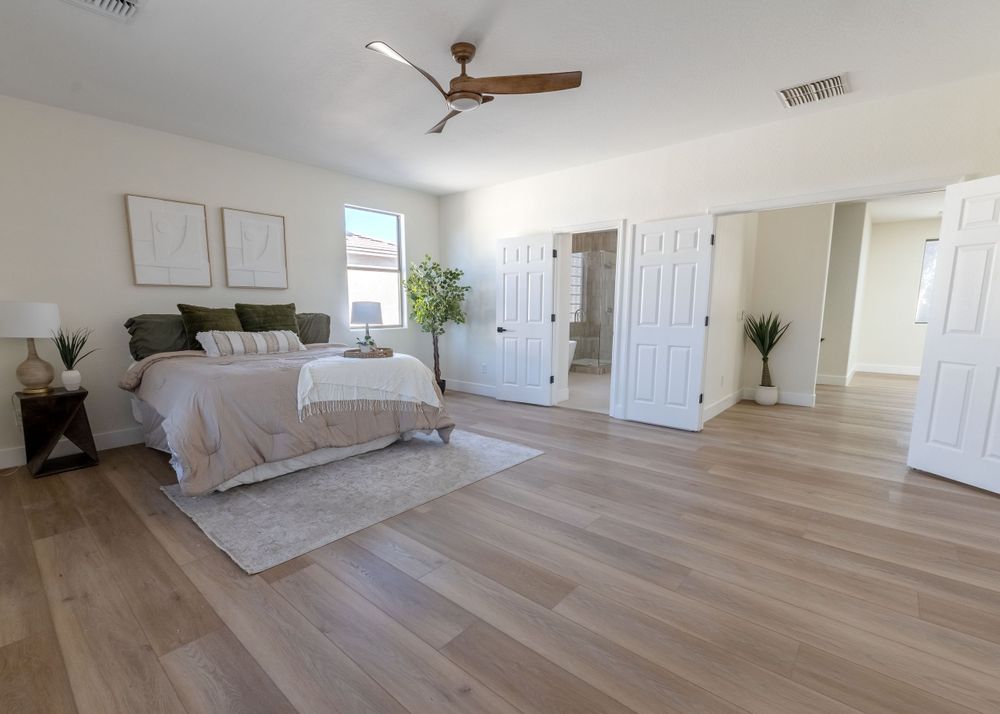 Spacious master bedroom with light wood floors, white bedding, and modern ceiling fan. MLS Photographer, Phoenix Arizona