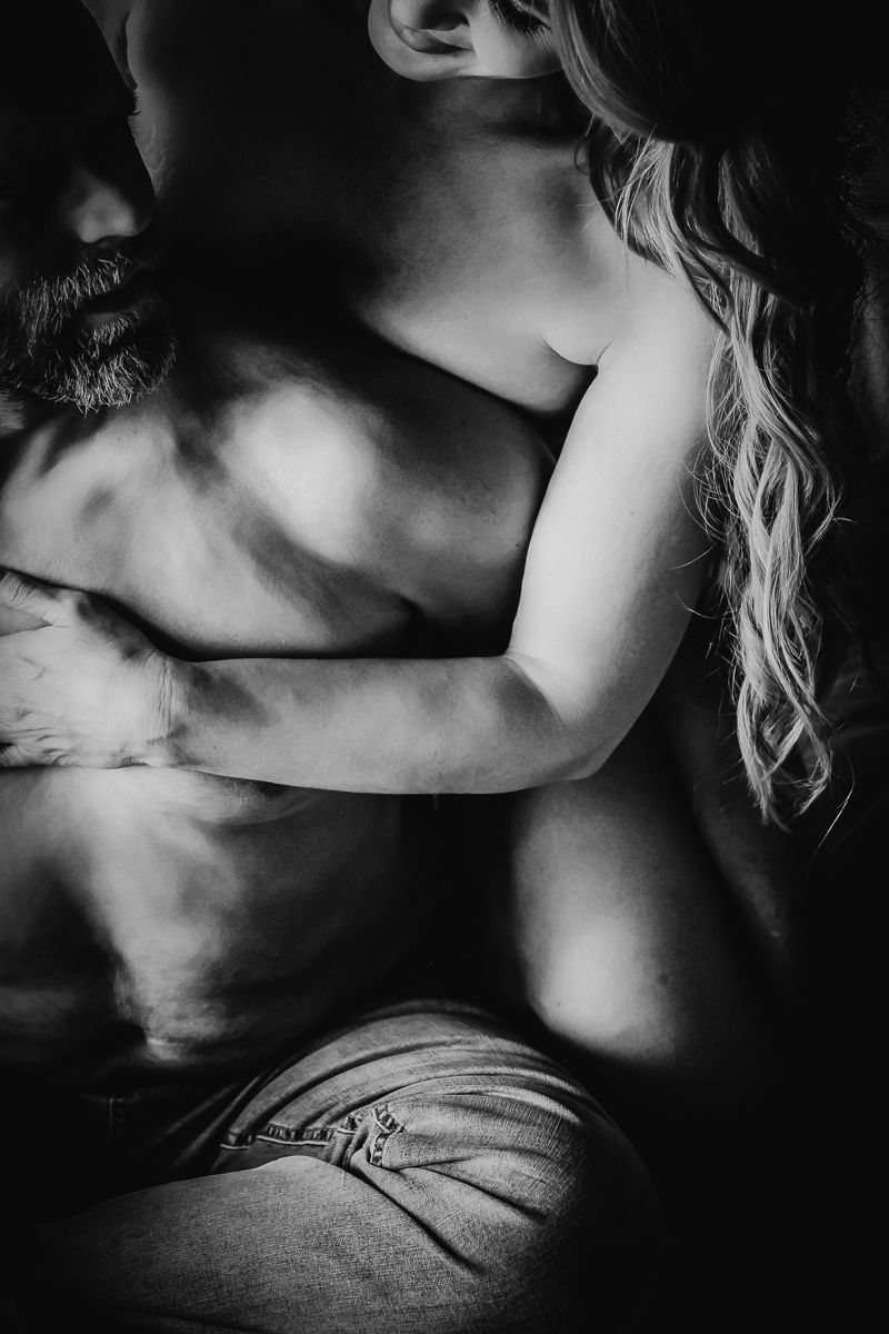 Intimate black and white artistic photograph of romantic couple in tender embrace.