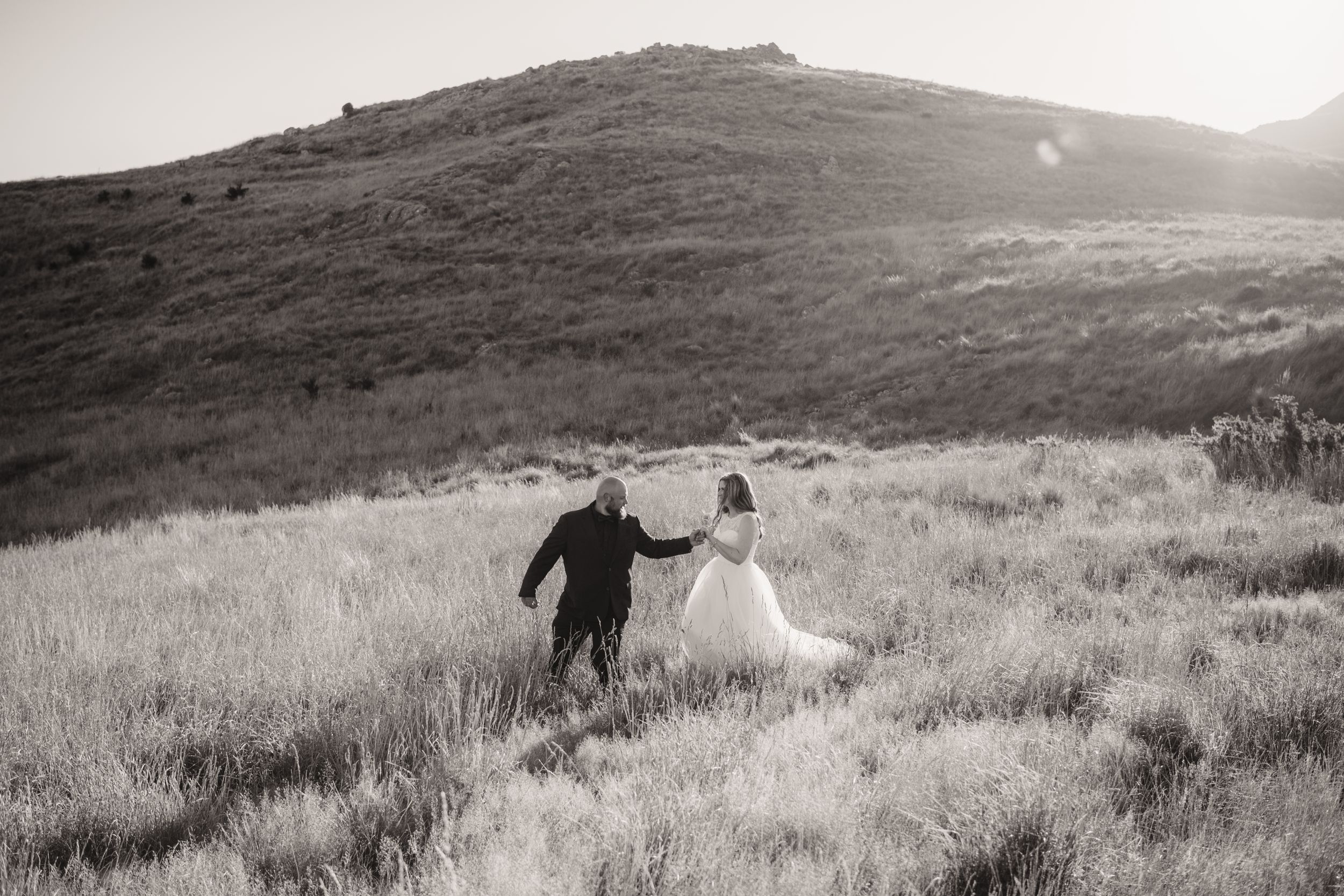 Running through grassy hillside during golden hour wedding photo session.