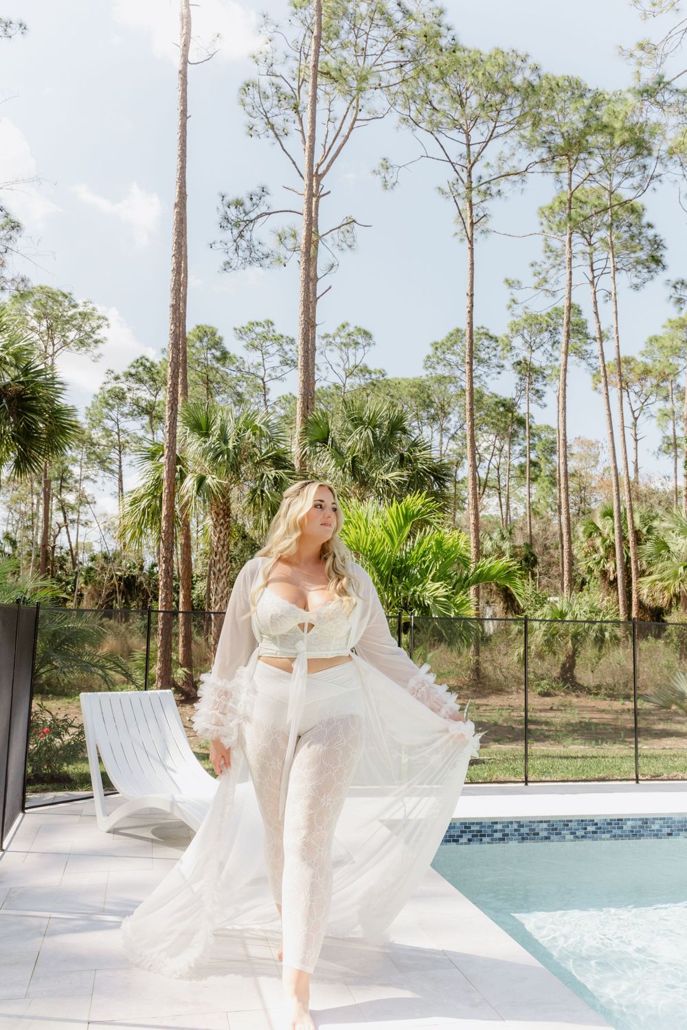 Flowing white robe movement captured poolside with tropical palms in background.