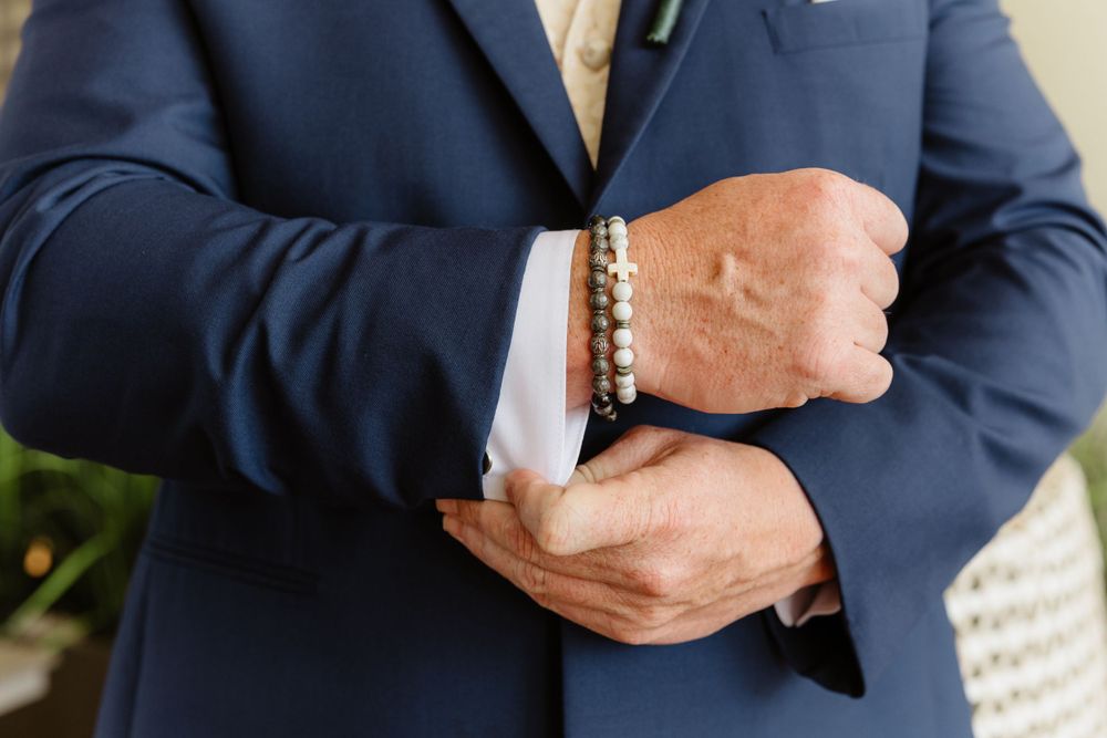 Detail shot of groom adjusting sleeve cuff with pearl bracelet.