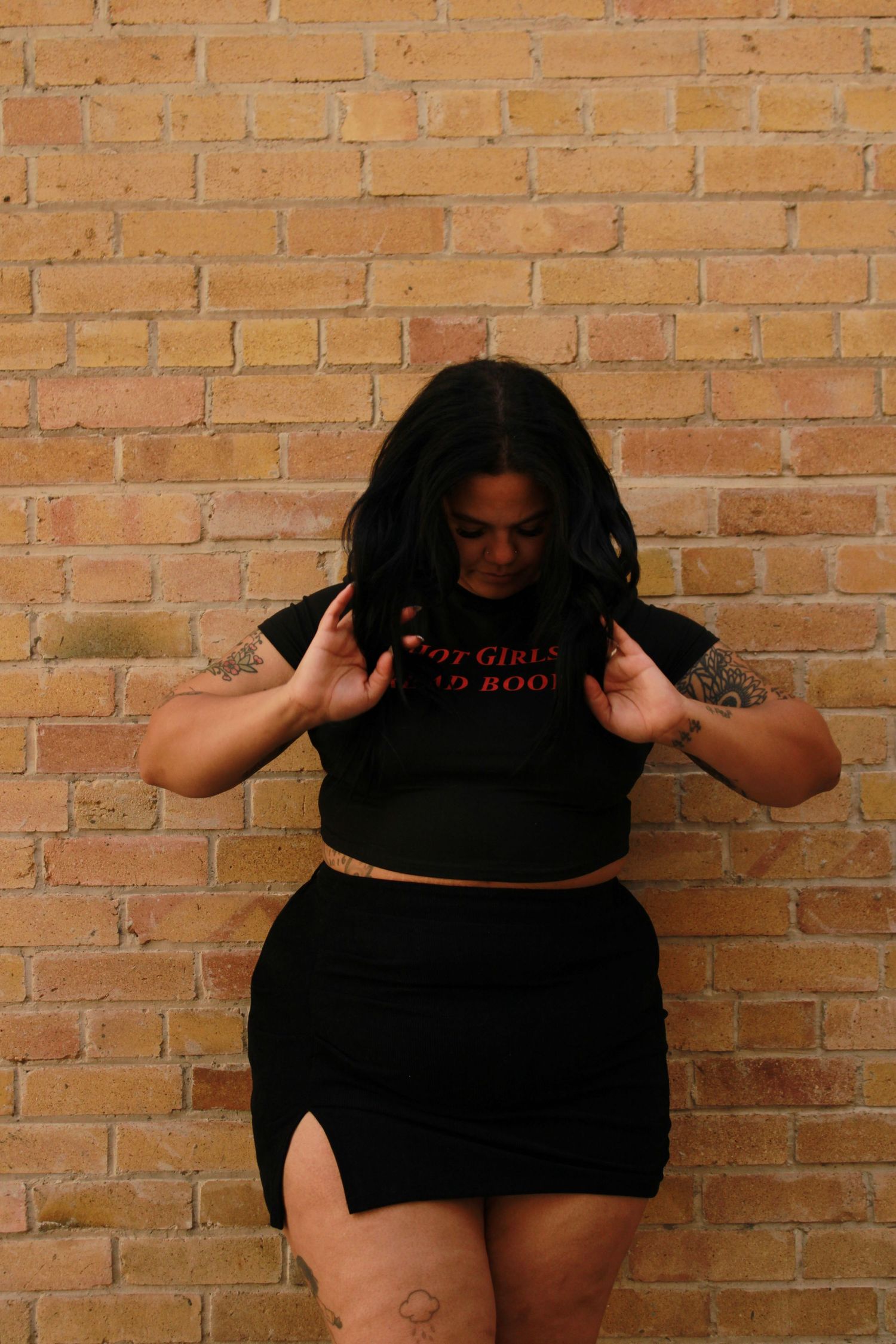 Fashion pose against brick wall wearing black crop top and mini skirt.