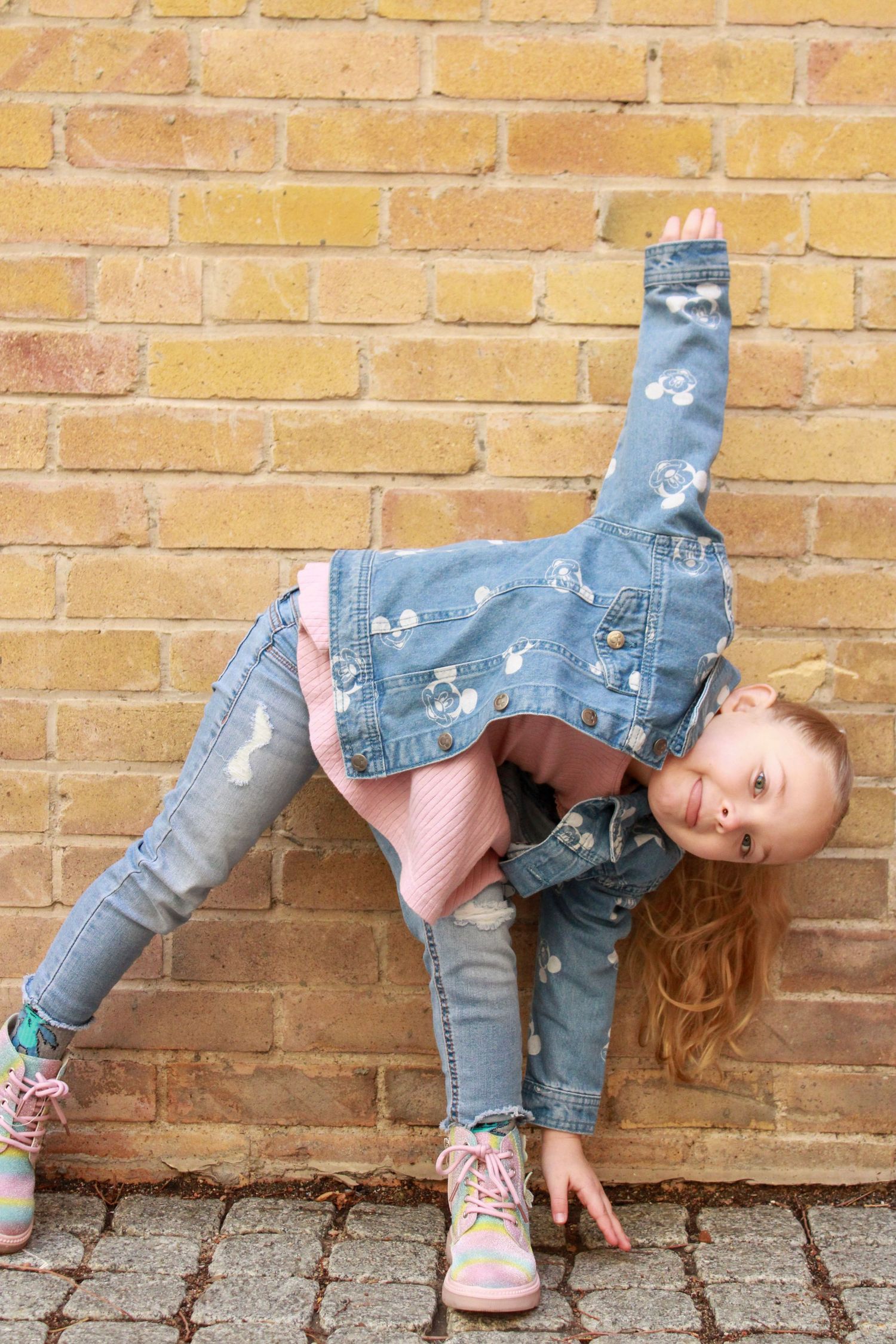 A playful pose against a yellow brick wall showing off fun dance moves.