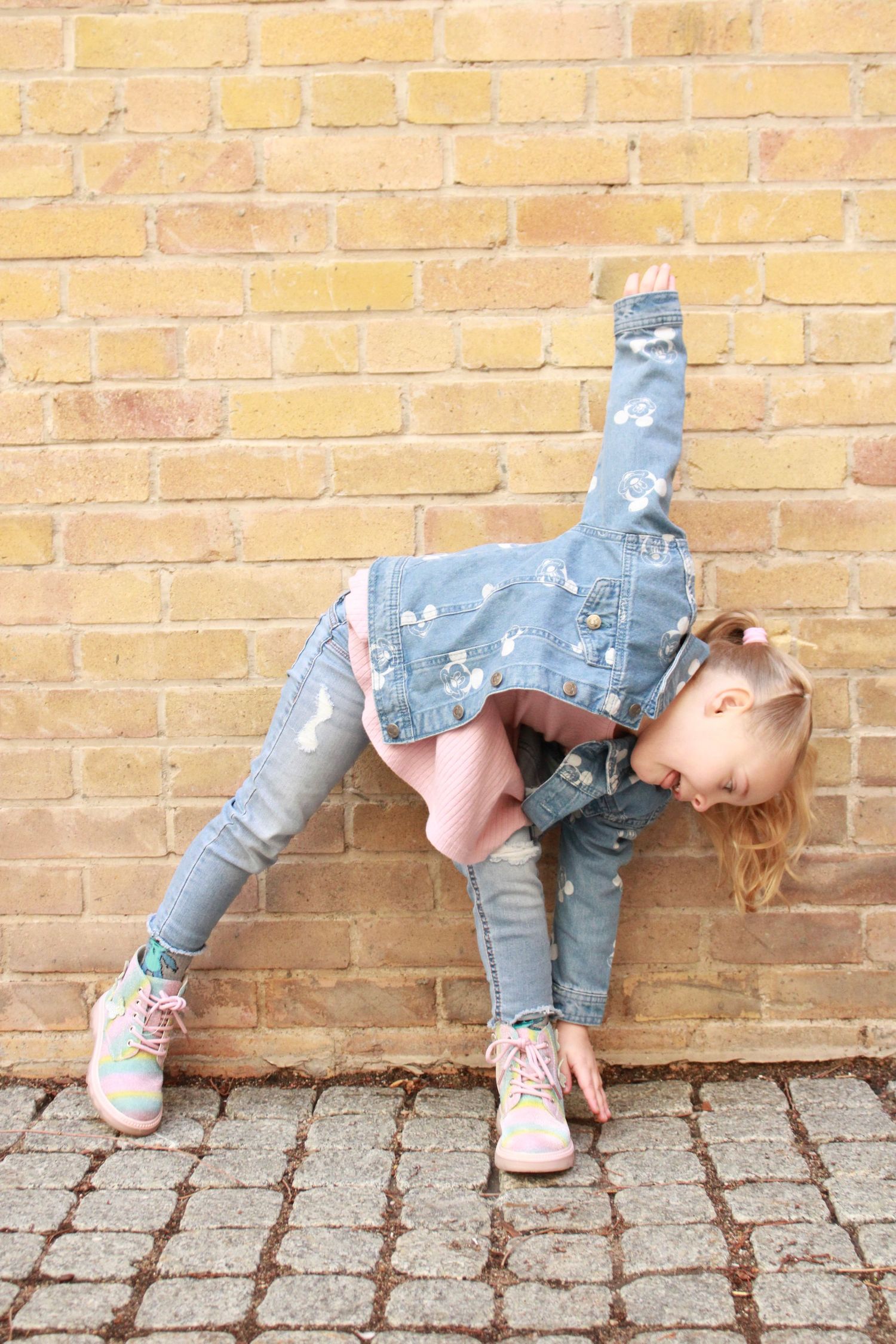 A creative dance pose showcasing movement against an urban brick backdrop.