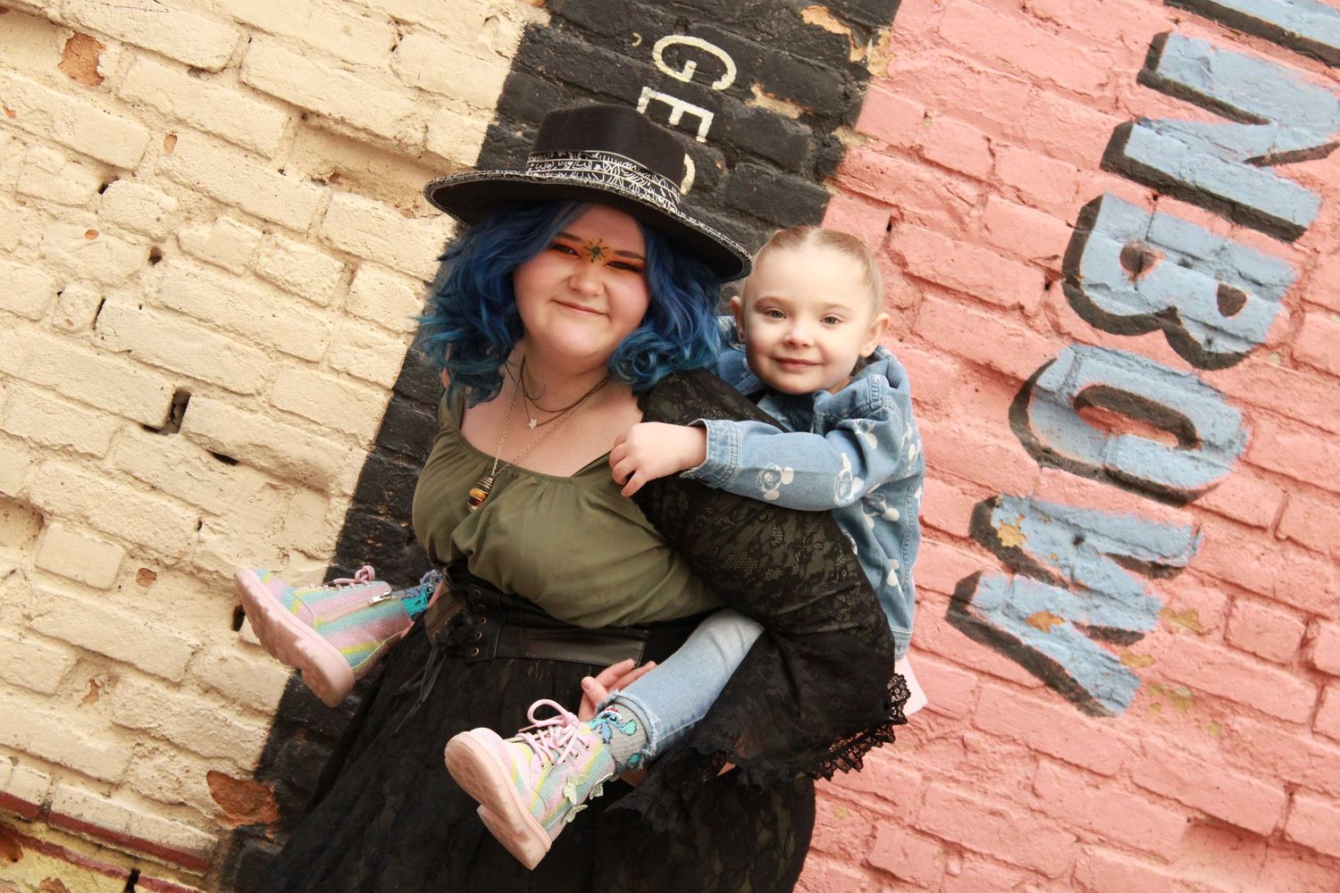 A sweet moment captured against multicolored brick walls with painted signage.