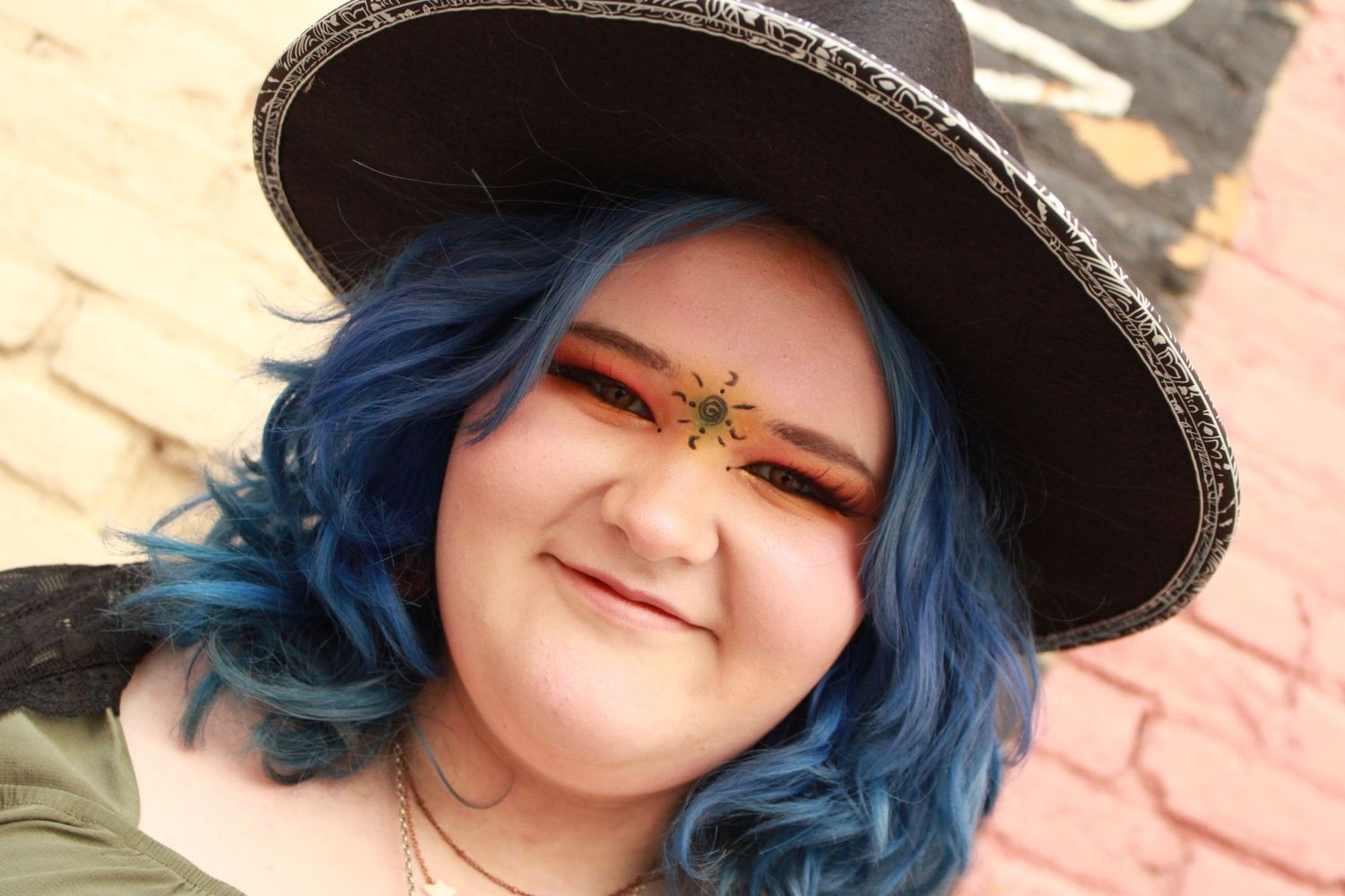 Portrait shot featuring blue hair, wide-brimmed hat, and face decorations.