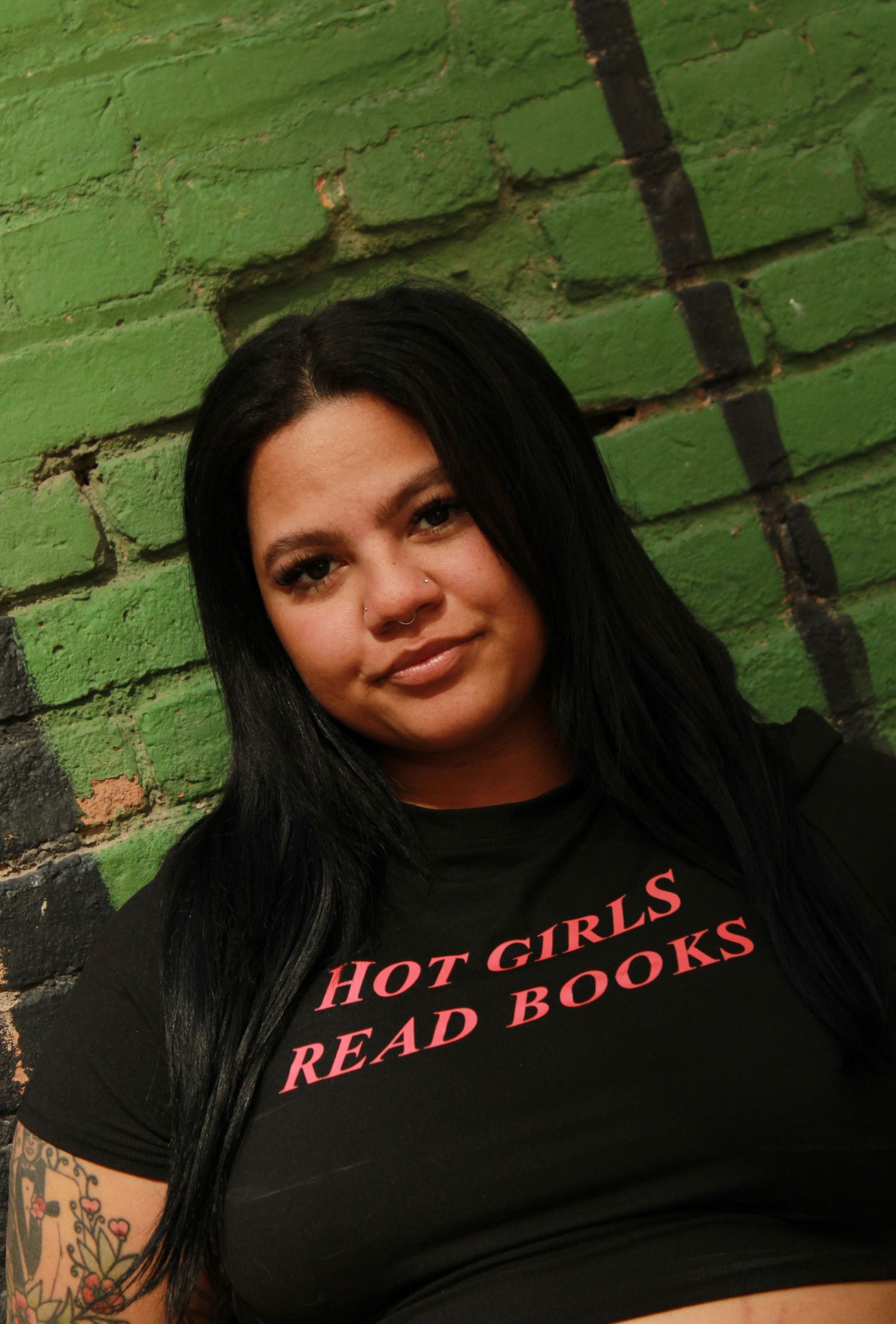 Portrait against green brick wall wearing black t-shirt with red lettering.