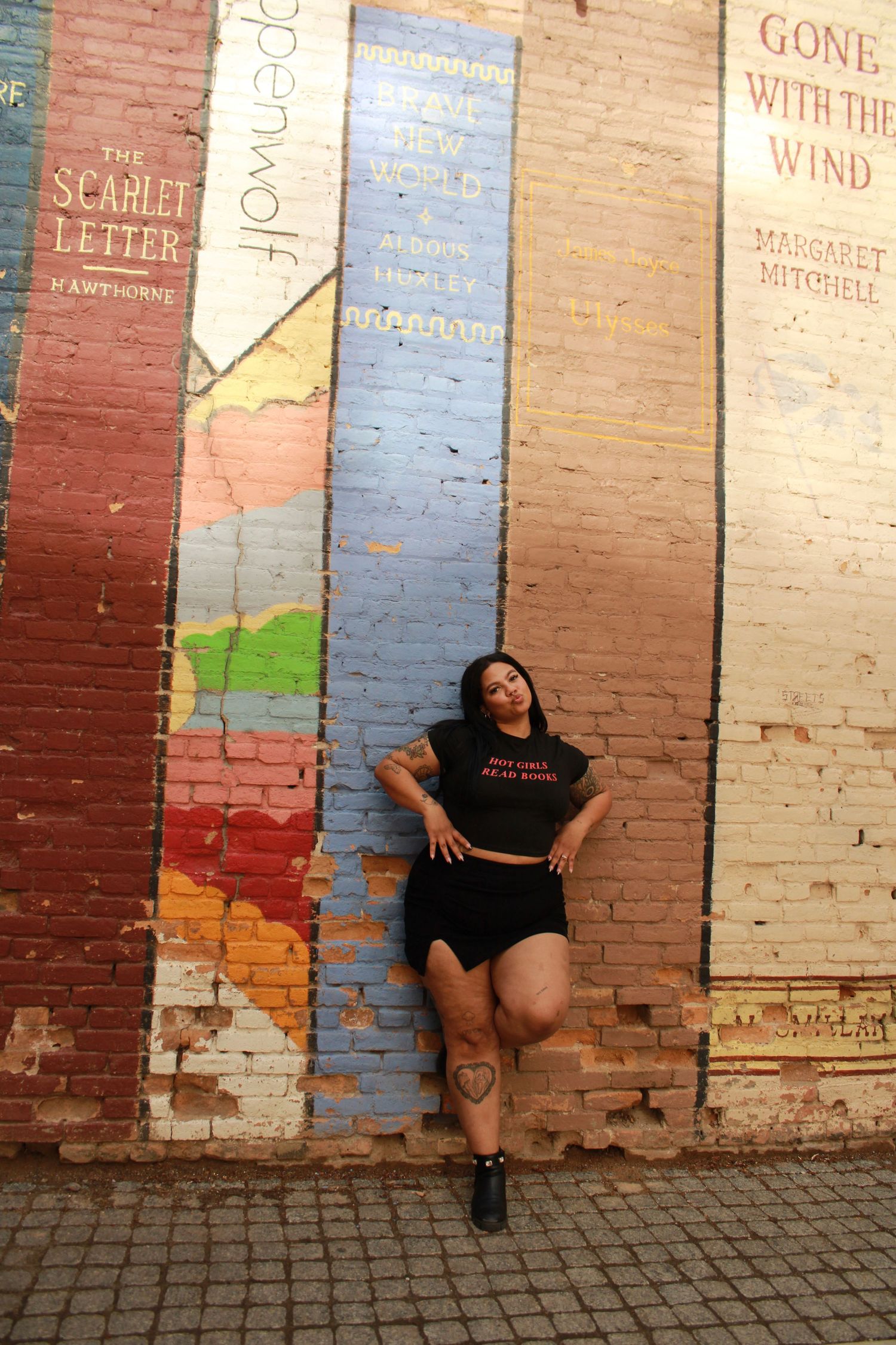 Street art featuring classic book titles with person posing in black outfit.