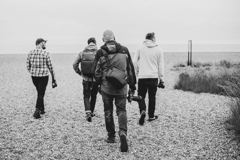 A group of people walking along a rocky coastal path on an overcast day. Aldeburgh Suffolk