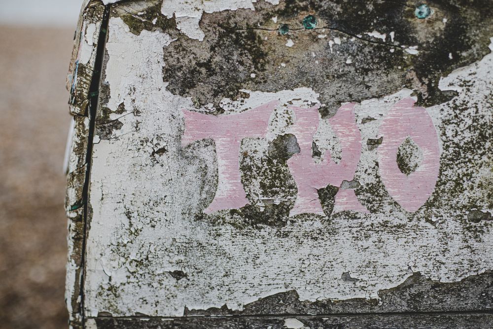 Close-up of weathered wall with pink text reading 'TWO' in graffiti style. Aldeburgh Suffolk