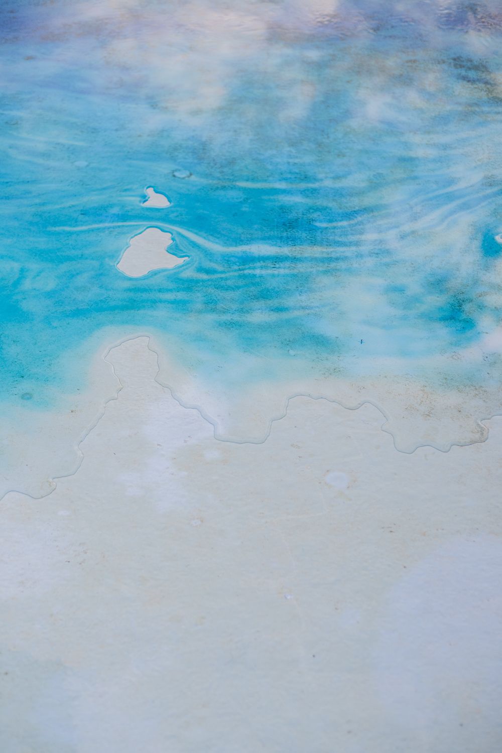 Abstract watercolor painting in shades of turquoise blue fading into white creating a dreamy oceanic effect.