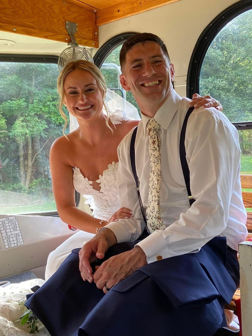 Wedding couple sitting together in a vintage wooden vehicle interior.
