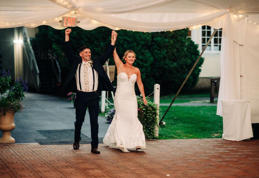 Wedding reception tent setup with elegant white draping and outdoor lighting.