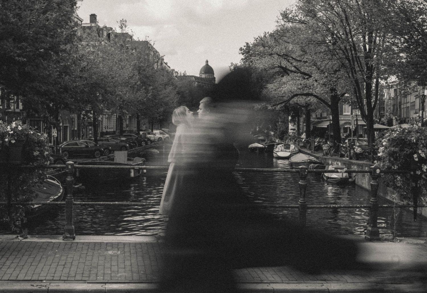 A monochrome couple photo capturing a tender moment by Amsterdam's iconic canals.