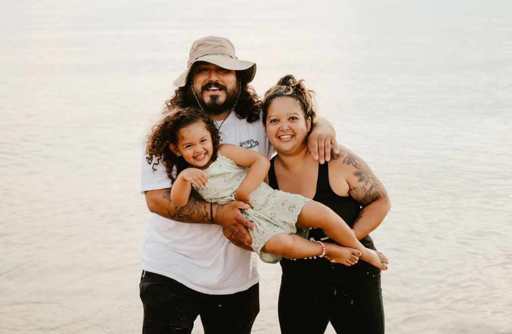 A happy family shares joyful moments together at the beach during sunset.